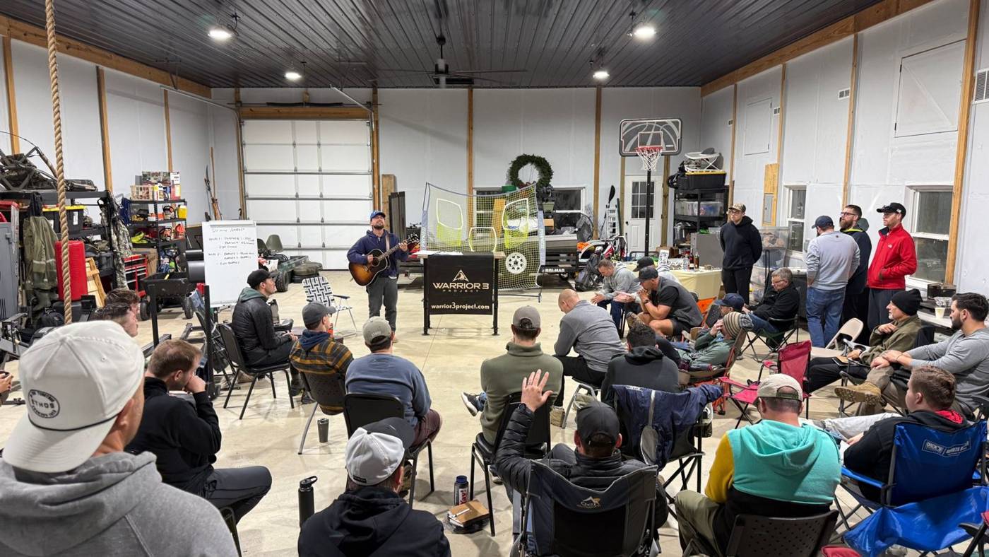 A man leading worship on guitar in the barn